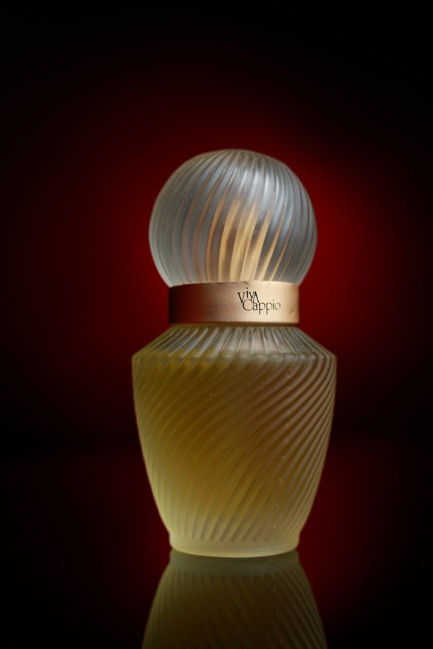 Close-up of an elegant perfume bottle with a textured glass design and warm lighting.